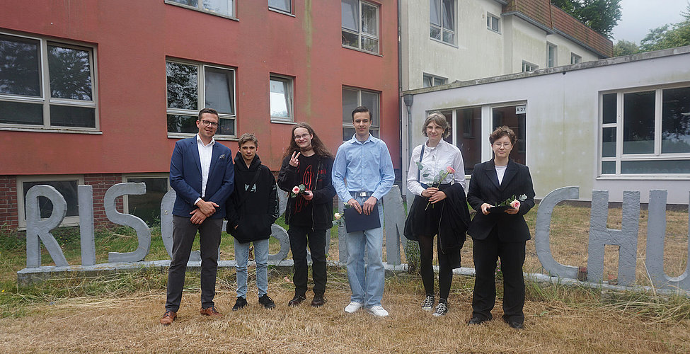 Klassenlehrer mit fünf Absolventinnen und Absolventen vor Rischborn-Schule